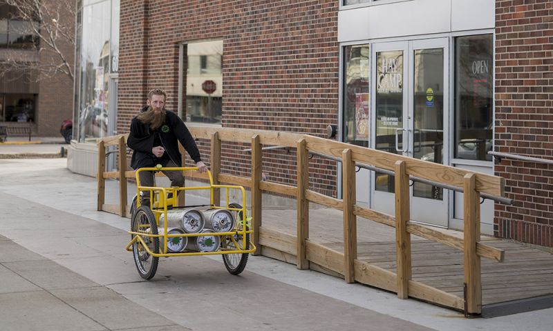 Ben Beck deliveres Hay Camp Brewery on bike in Downtown Rapid City South Dakota